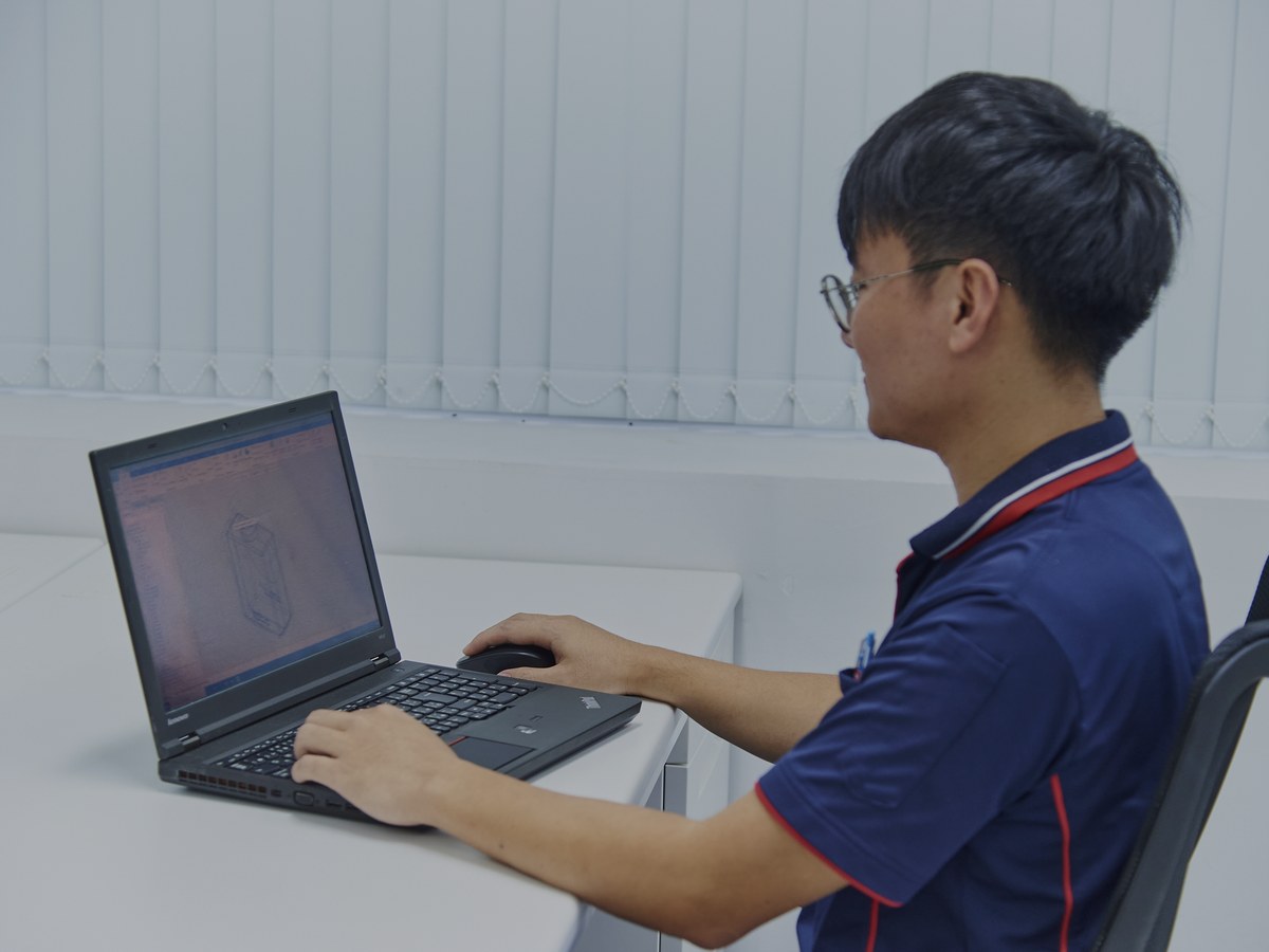 ノートパソコンで3Dイメージを確認しながら設計作業を行うスタッフ